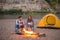 People, tourism and nature concept - Man embrace woman sitting near a fire