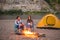 People, tourism and nature concept - Romantic evening, man embrace woman sitting near a campfire