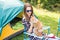 People, tourism and nature concept - Woman in sunglasses stroking a cat sitting near the tent