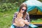 People, tourism and nature concept - Woman in sunglasses stroking a cat sitting near the tent