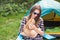 People, tourism and nature concept - Woman in sunglasses stroking a cat sitting near the tent