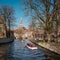 People in a tourist boat next to the Beguinage in the city of Bruges