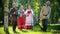 People in traditional Russian clothes are dancing on the field - one of them plays the accordion music