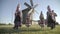 People in traditional russian clothes dancing and singing song outdoor on traditional antique wooden windmill background