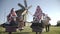 People in traditional russian clothes dancing and singing song outdoor on traditional antique wooden windmill background