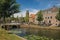 People on tree-lined canal, brick houses and bridge with sunny blue sky in Weesp.