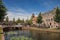 People on tree-lined canal, brick houses and bridge with sunny blue sky in Weesp.