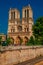 People, tree-lined Seine River and gothic Notre-Dame Cathedral at Paris.