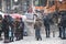 People waiting at crossroad on a snowy city street during heavy snow fall, and a snow removal truck is driving past