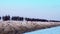 People walk along long rocky pier near tranquil azure ocean