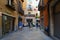 People walk along narrow street in historic center of Girona, Spain