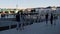 People walk along paved embankment of large city near river