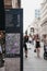 People walk past directions and map board on Poultry, City of London, UK.