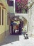People walk past shops and old arches in a narrow street in rhodes town in bright sunlight