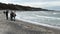 People walking along coastal beach of Darss peninsula at village Ahrenshoop. Sand dunes with reed