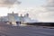 People walking along the Malecon being sprayed by wave crashing against the sea wall during a hazy late afternoon