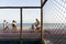 People walking along the shore of Paciencia beach behind a field with mesh wires in Rio Vermelho