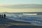 People walking bonita beach with surfer at sunrise