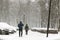 People walking through city street covered with snow during heavy snowfall. Blizzard in town at winter. Natural