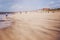 People walking and jogging along the beach against strong winds carrying sand at North Sea coast, Belgium