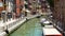 People walking narrow Venetian street, tourism and holidays, boats on water