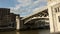 People walking old stone bridge across river, industrial district architecture