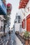 People walking past building with colourful detail on a narrow street in Hora Mykonos Town, Greece