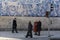 People walking in the sidewalk, preparing to cross the street. Red traffic light. Traditional portuguese tiles in the background.