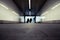 People walking through an underground subway corridor with suitcases trolley