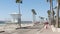 People walking on waterfront promenade, pacific ocean tropical beach with palm trees. California USA