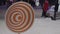 People walks behind orange spinning hypnotic wheel on snow at winter street