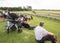 People watching a motorsport race at a race track from a grassed embankment in the sunshine