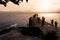 People watching the sunset over a large rock