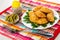 Pepper, bowl with green peas, plate with small patties and parsley, fork on napkin on wooden table