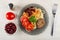 Pepper, tomato, bowl with beans, plate with spaghetti, cutlet, beans, tomato, leaf of parsley, fork on table. Top view