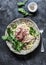 Peppered steak pasta. Spaghetti pasta with sliced beef steak and rocket salad on a dark background, top view