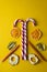 Peppermint candy canes with dried fruits on a yellow background