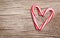 Peppermint Candy Canes in Heart Shape on wooden background.