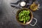 Peppers de padron or fresh green pimientos in an iron pan with olive oil and coarse sea salt, ingredients for a Spanish tapa or