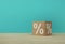 Percentage sign symbol icon with paper cube block on wooden table and blue background