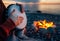 Percussionist plays djembe on the seashore near fire, hands close up