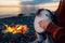 Percussionist plays djembe on the seashore near fire, hands close up