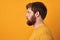 Perfect beard. Close-up of young bearded man standing against yellow isolated background.