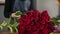 Perfect bunch of red roses on the table. Closeup view of hands of female florist arranging modern bouquet using