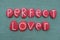 Perfect lover, creative phrase composed with red colored stone letters over green sand