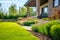 Perfect manicured lawn and flowerbed with shrubs in sunshine, on a backdrop of residential house backyard