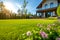 Perfect manicured lawn and flowerbed with shrubs in sunshine, on a backdrop of residential house backyard