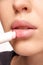 Perfect natural lip makeup. Close up photo of woman applying hygienic lip balm. Moisturizing chap stick for dry lips.