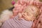 Perfect newborn baby girl in pink blanket in a wicker basket decorated with beautiful pink tulips