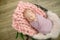 Perfect newborn baby girl in pink blanket in a wicker basket decorated with beautiful  pink tulips